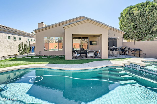 view of pool featuring a patio, a lawn, fence, and a pool with connected hot tub