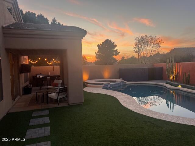 view of swimming pool featuring a pool with connected hot tub, a patio area, a lawn, and a fenced backyard