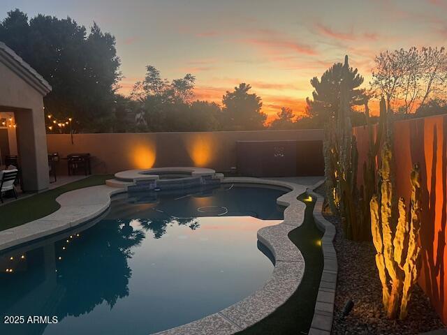 view of swimming pool featuring a pool with connected hot tub, a patio area, and a fenced backyard