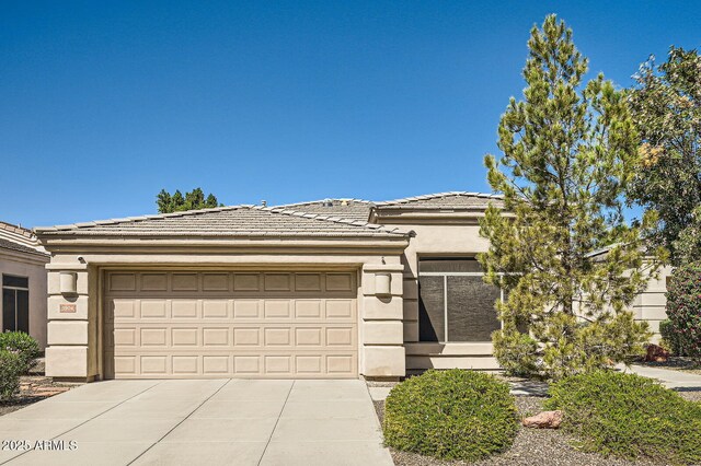 prairie-style house with driveway, an attached garage, a tile roof, and stucco siding