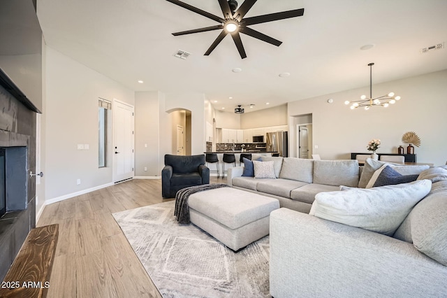 living room featuring light wood finished floors, a fireplace, visible vents, and baseboards