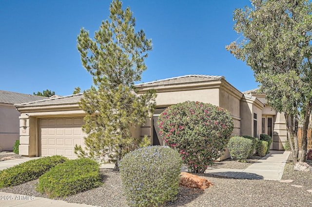 view of front facade featuring a tile roof, an attached garage, and stucco siding