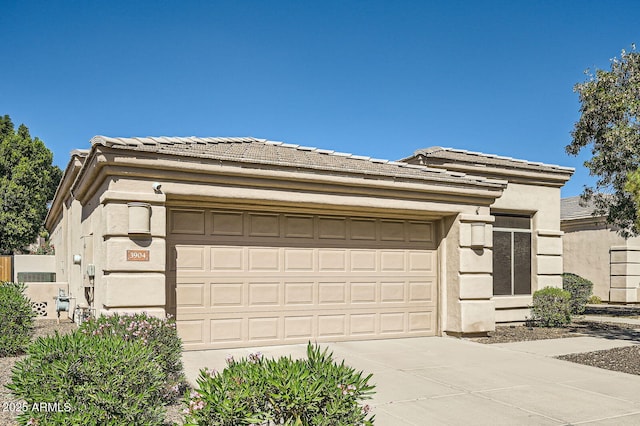 prairie-style home featuring driveway, a tiled roof, an attached garage, and stucco siding