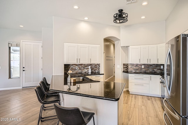 kitchen featuring stainless steel appliances, a peninsula, a sink, and white cabinets