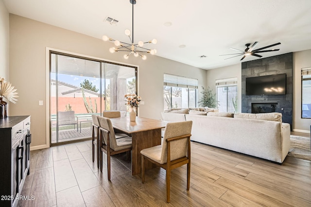 dining room with baseboards, visible vents, a large fireplace, and light wood finished floors