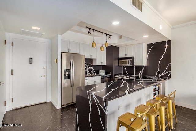 kitchen featuring stainless steel appliances, a breakfast bar area, white cabinets, and kitchen peninsula