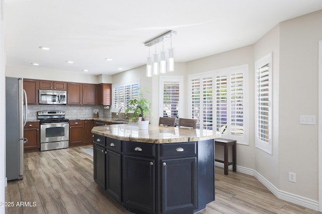 kitchen with sink, backsplash, hanging light fixtures, a center island, and stainless steel appliances