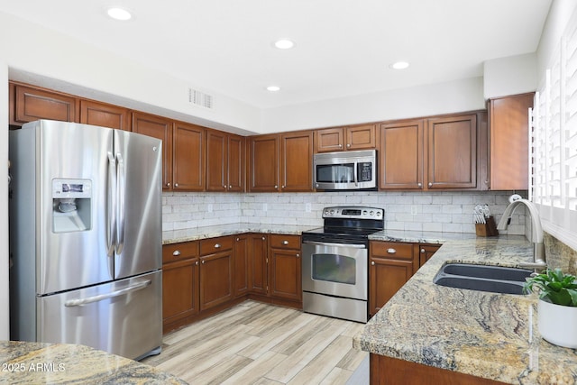 kitchen featuring light stone counters, sink, decorative backsplash, and appliances with stainless steel finishes