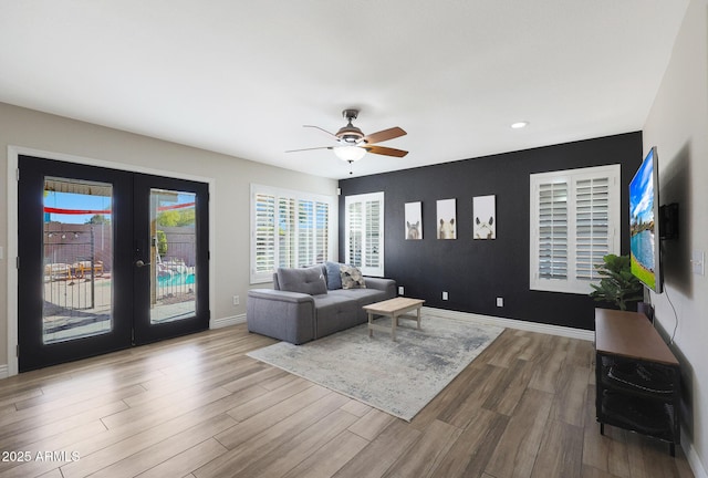 living room with french doors, ceiling fan, and light hardwood / wood-style flooring