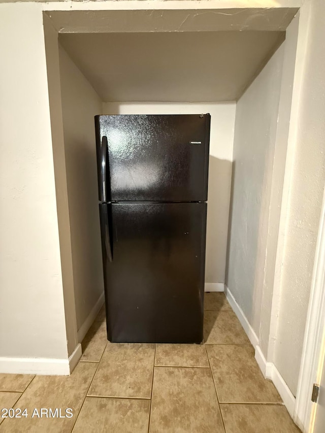 kitchen with black fridge and light tile patterned flooring