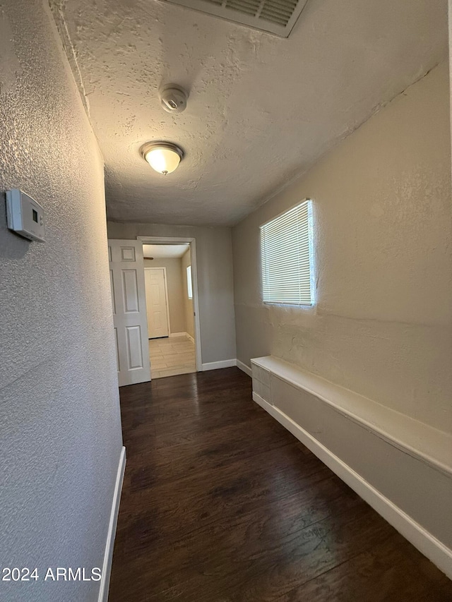 hall with a textured ceiling and dark hardwood / wood-style floors