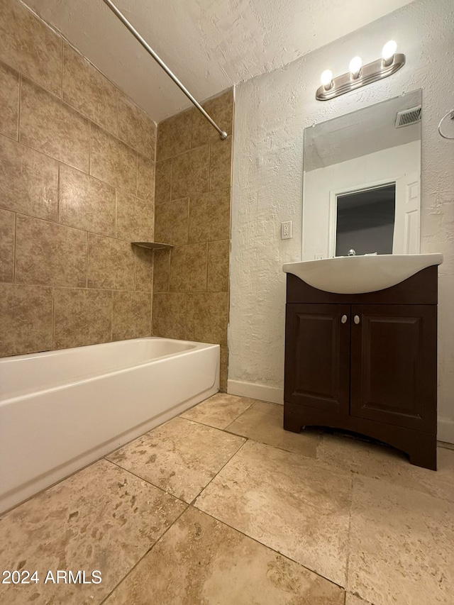 bathroom with vanity, a textured ceiling, and tiled shower / bath