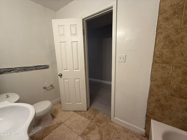 bathroom featuring tile patterned flooring, toilet, and a tub to relax in