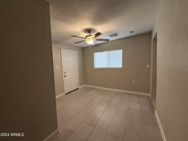 unfurnished room featuring a textured ceiling, light hardwood / wood-style flooring, and ceiling fan