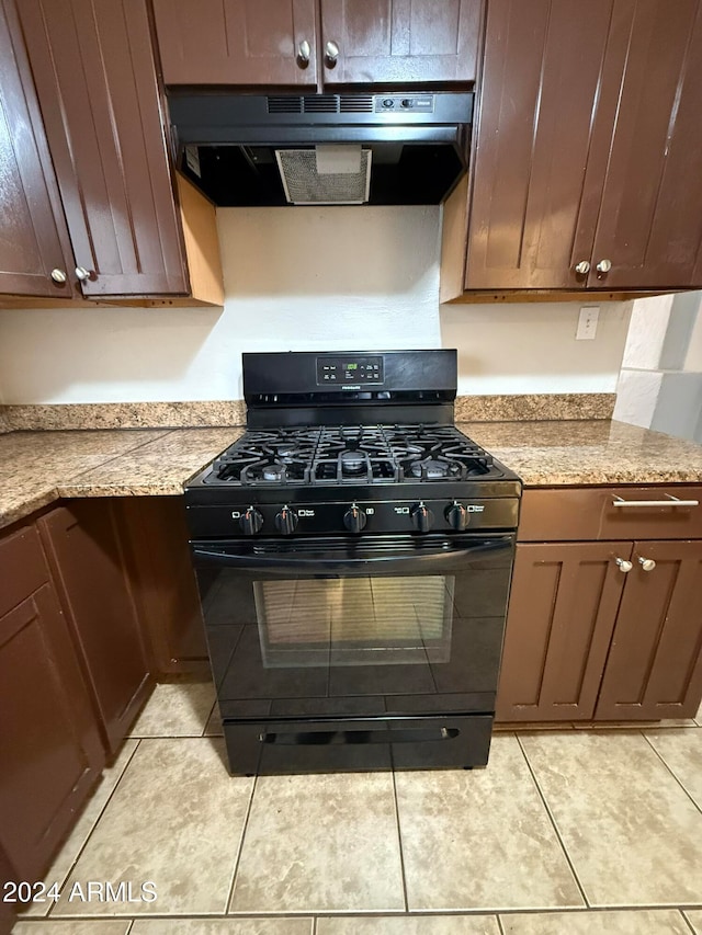 kitchen featuring gas stove, light tile patterned flooring, and light stone countertops