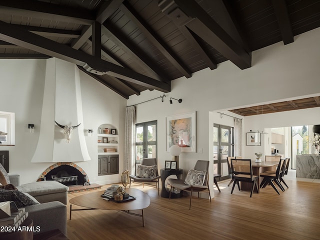 living room featuring built in features, high vaulted ceiling, a fireplace, beamed ceiling, and french doors