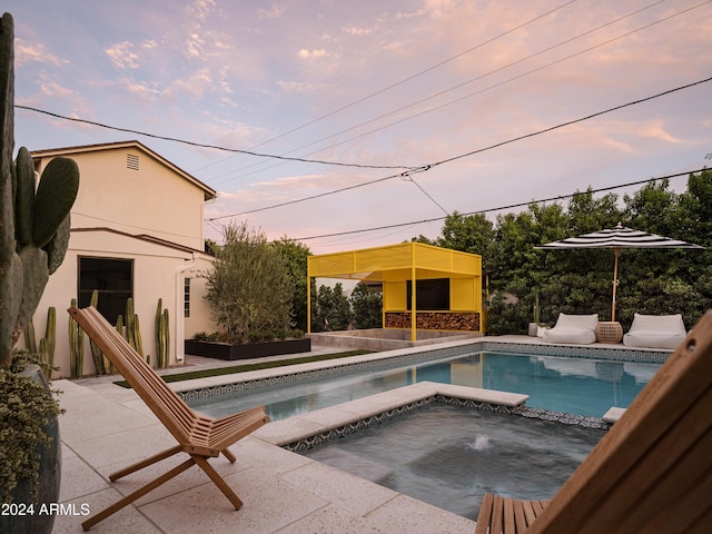 pool at dusk with an in ground hot tub