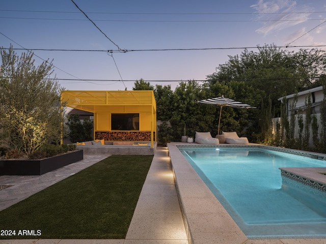 pool at dusk with a yard and a patio