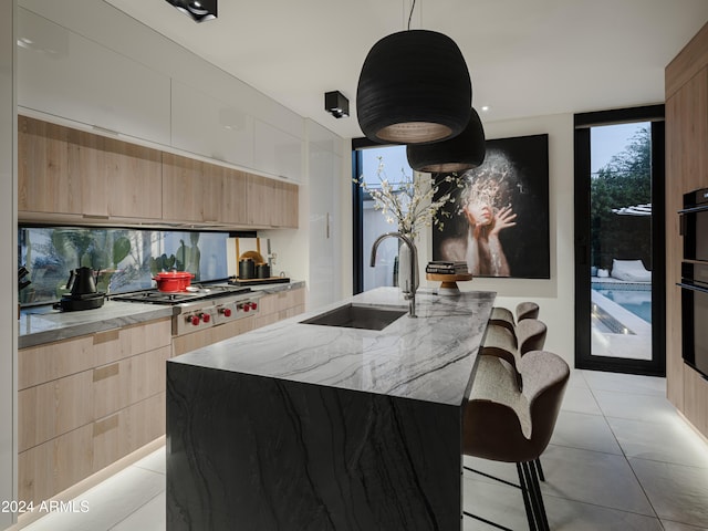 kitchen featuring pendant lighting, sink, a breakfast bar area, expansive windows, and a kitchen island with sink