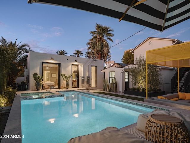 pool at dusk featuring an outdoor structure and a patio area