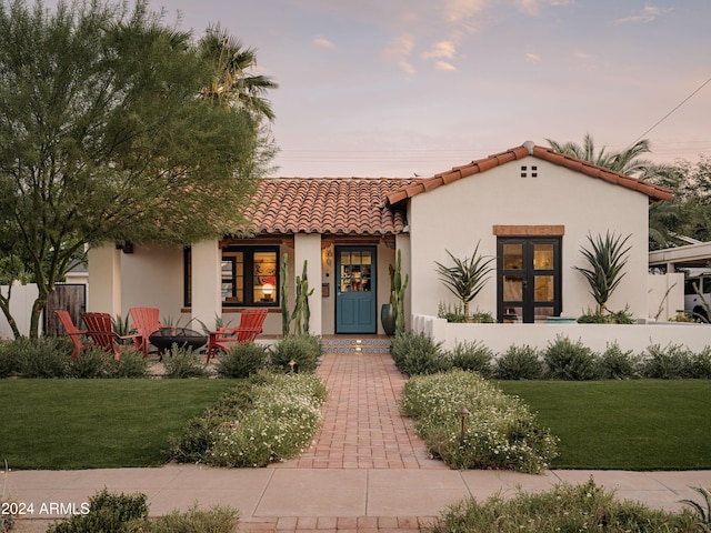 mediterranean / spanish home with a fire pit and a lawn