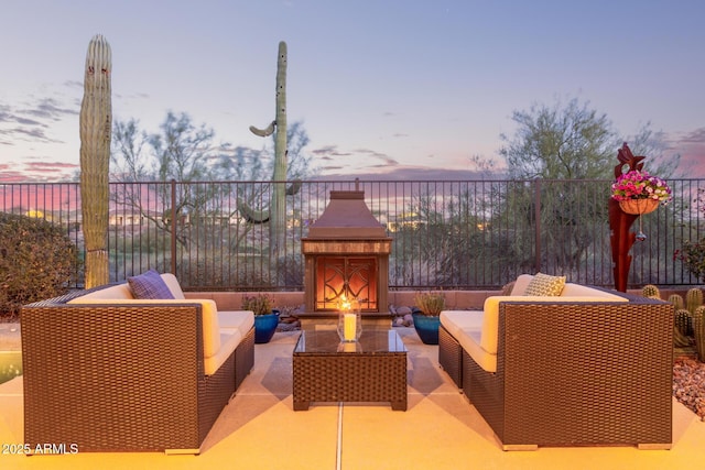 patio terrace at dusk with an outdoor living space with a fireplace