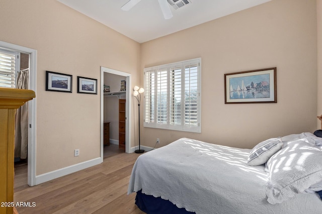 bedroom with a spacious closet, a closet, ceiling fan, and light wood-type flooring