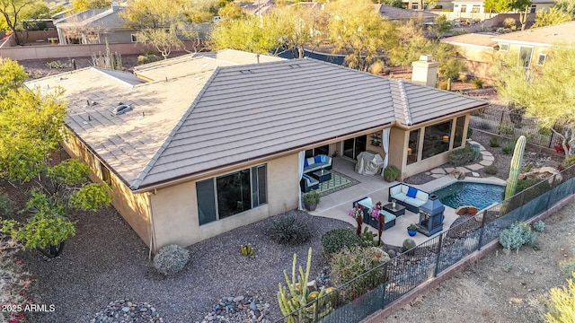 back of property with a fenced in pool and a patio