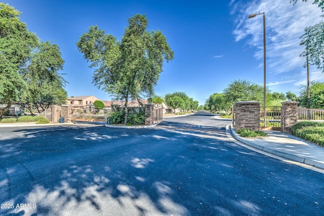 view of street featuring a gate, curbs, and a gated entry