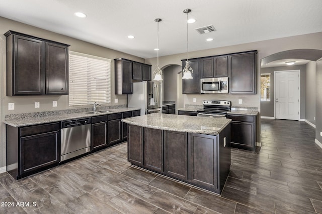 kitchen with dark brown cabinets, visible vents, arched walkways, and stainless steel appliances