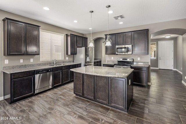kitchen with stainless steel appliances, arched walkways, a sink, dark brown cabinetry, and recessed lighting