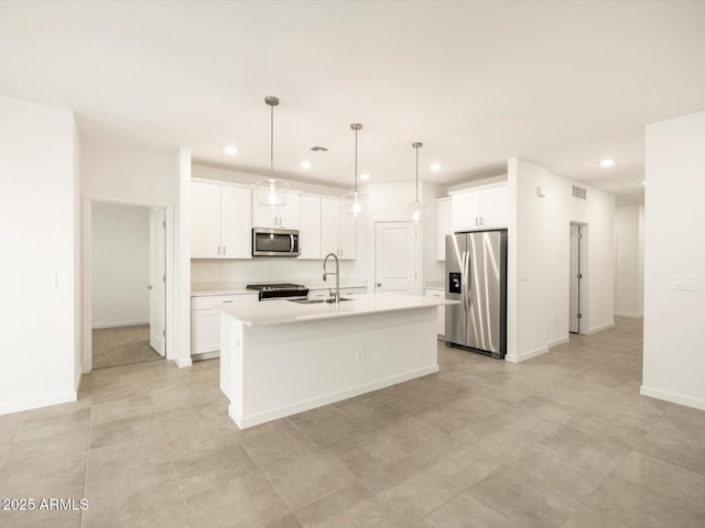 kitchen featuring white cabinetry, sink, decorative light fixtures, a kitchen island with sink, and appliances with stainless steel finishes