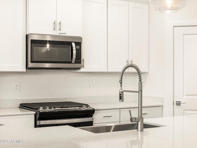 kitchen featuring white cabinets, light stone countertops, sink, and appliances with stainless steel finishes