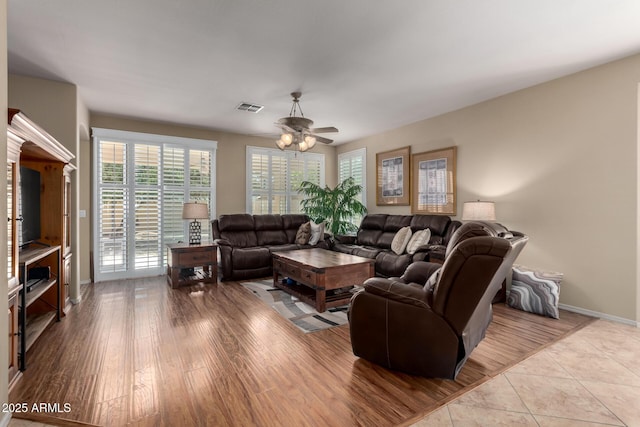 living area with ceiling fan, wood finished floors, visible vents, and baseboards