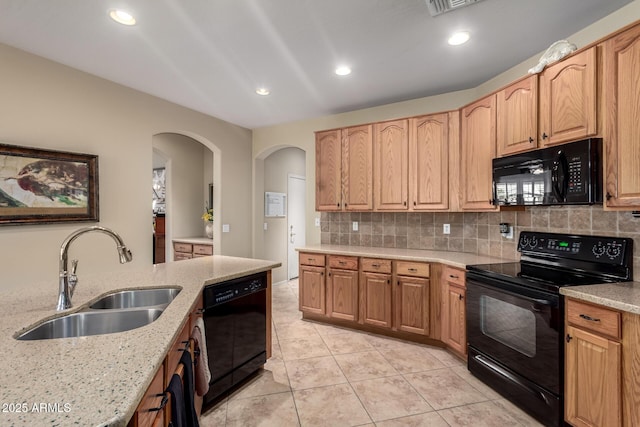 kitchen with black appliances, a sink, light stone counters, recessed lighting, and decorative backsplash