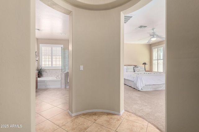 hall with light tile patterned flooring, baseboards, visible vents, and light carpet