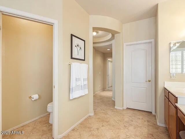 bathroom featuring baseboards, toilet, and vanity