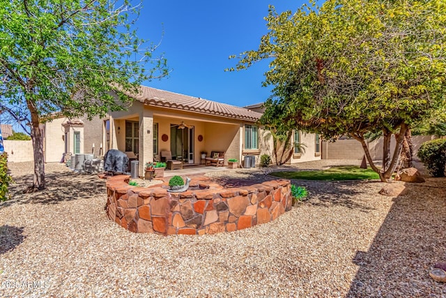 rear view of house with stucco siding, a patio, an outdoor fire pit, and a tile roof