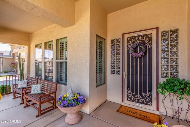 view of exterior entry featuring stucco siding and a porch