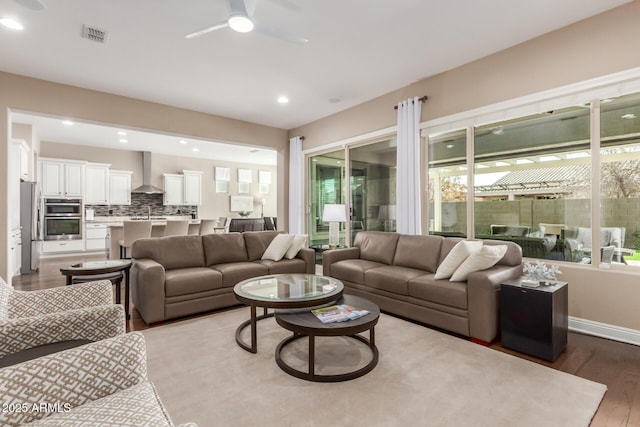 living room featuring ceiling fan, light hardwood / wood-style floors, and a wealth of natural light