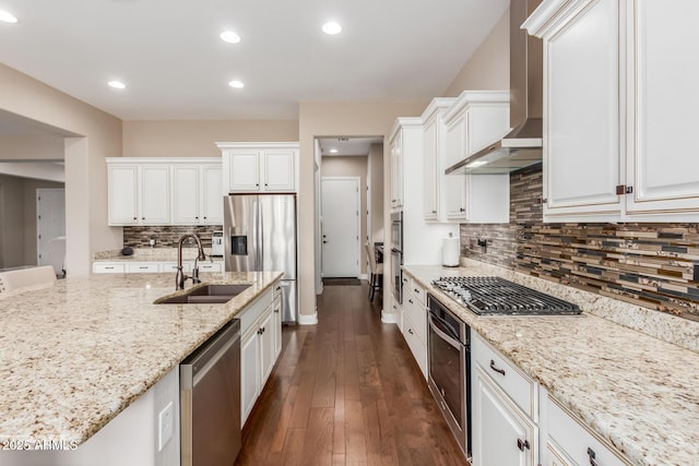 kitchen featuring appliances with stainless steel finishes, white cabinets, light stone counters, and wall chimney exhaust hood