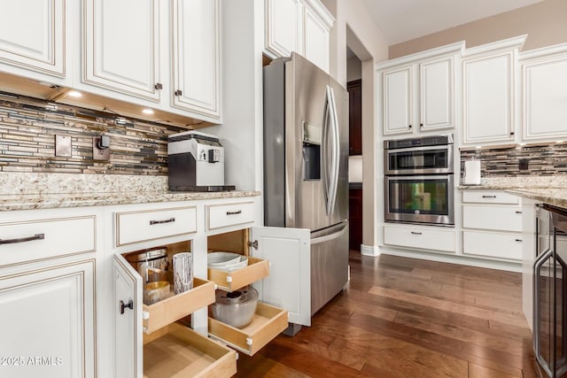 kitchen featuring light stone counters, appliances with stainless steel finishes, dark hardwood / wood-style flooring, decorative backsplash, and white cabinets