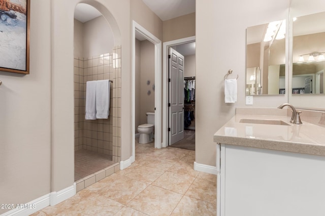 bathroom with tile patterned flooring, vanity, tiled shower, and toilet