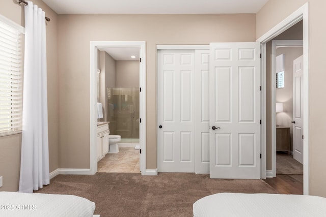 carpeted bedroom with ensuite bath and a closet