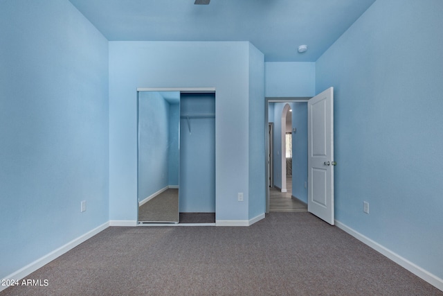 unfurnished bedroom featuring a closet and dark carpet