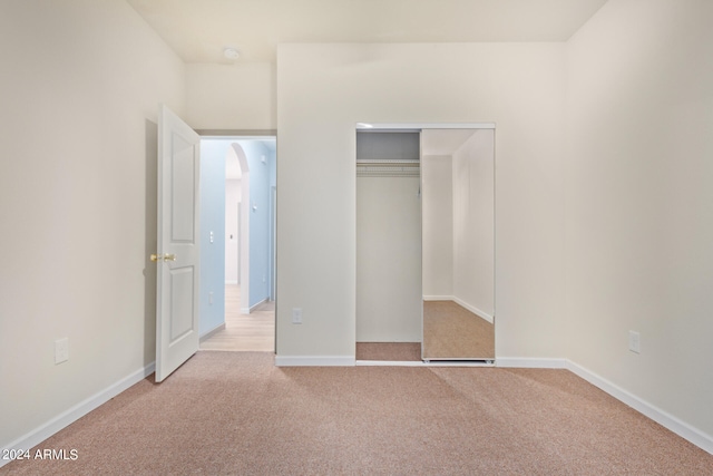 unfurnished bedroom featuring a closet and light colored carpet