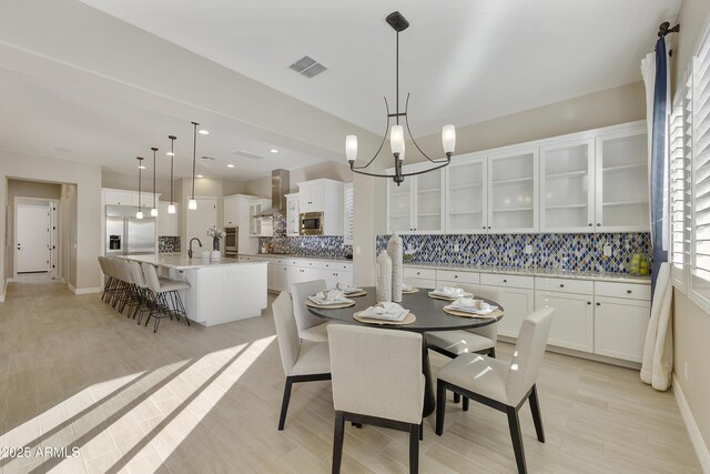 dining space featuring sink, a chandelier, and light hardwood / wood-style floors