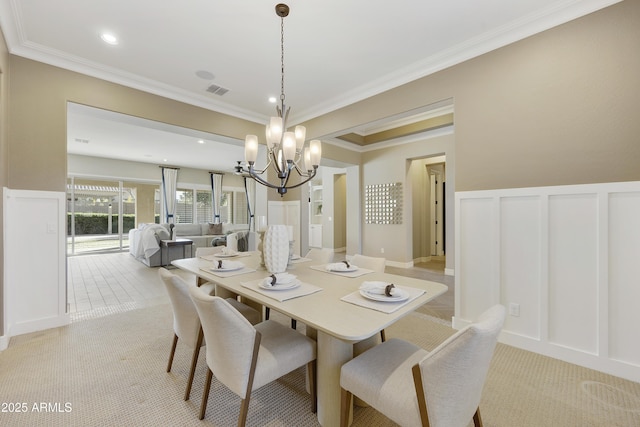 carpeted dining area with ornamental molding and an inviting chandelier