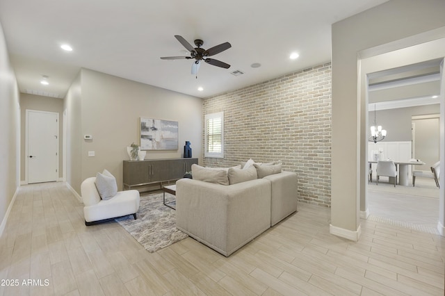 living room featuring brick wall and ceiling fan with notable chandelier