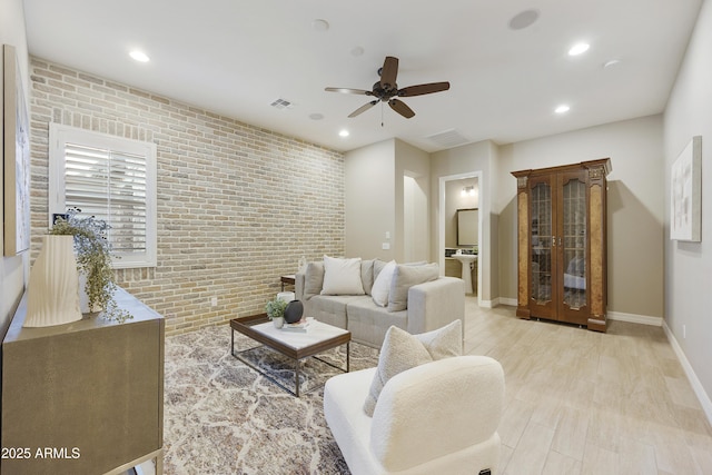 living room featuring ceiling fan, brick wall, and light hardwood / wood-style flooring